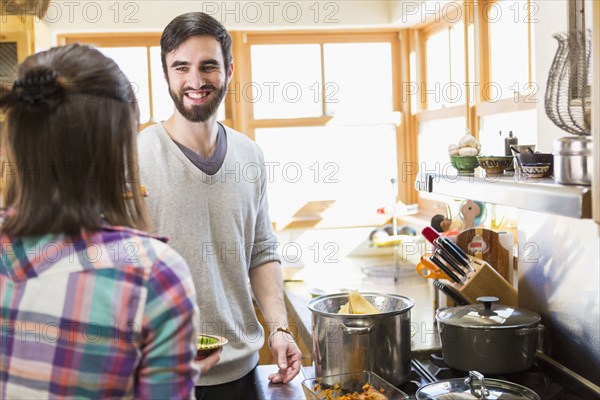 Hispanic couple cooking in kitchen