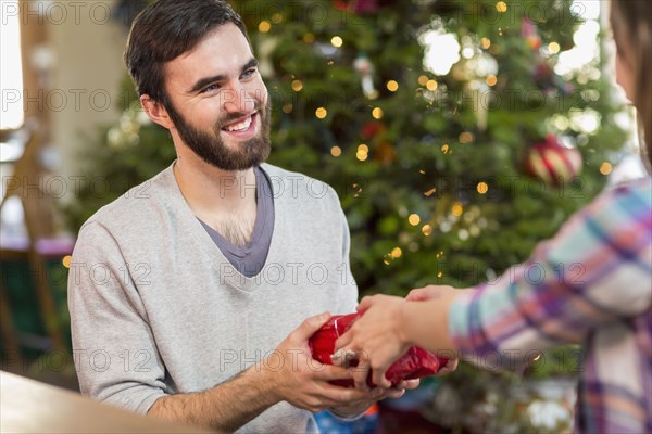 Hispanic couple exchanging Christmas gifts