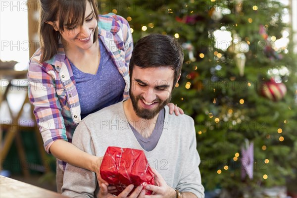 Hispanic couple exchanging Christmas gifts