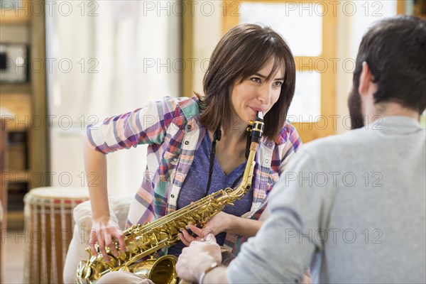 Hispanic man watching girlfriend playing saxophone
