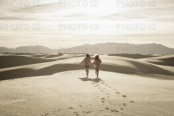 Caucasian children running in desert
