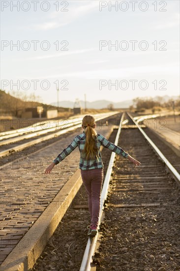 Caucasian girl balancing on train tracks