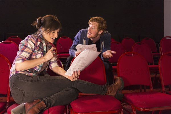 Actors rehearsing in red theater seats