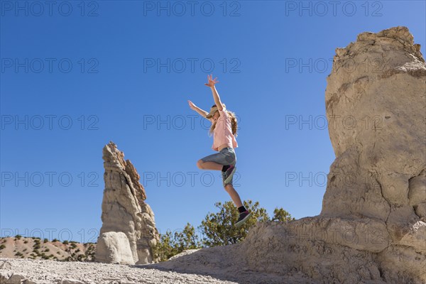 Caucasian girl jumping off rock formation