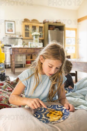 Caucasian girl eating on living room sofa