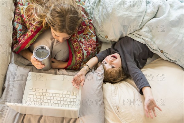 Caucasian children relaxing in bed with laptop