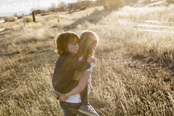 Caucasian girl carrying brother piggyback