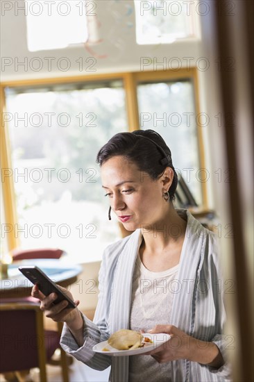 Businesswoman using cell phone and headset in office
