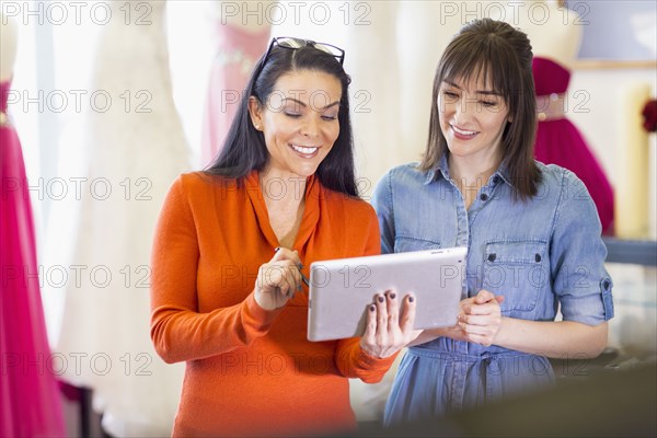 Hispanic entrepreneurs using digital tablet in bridal shop