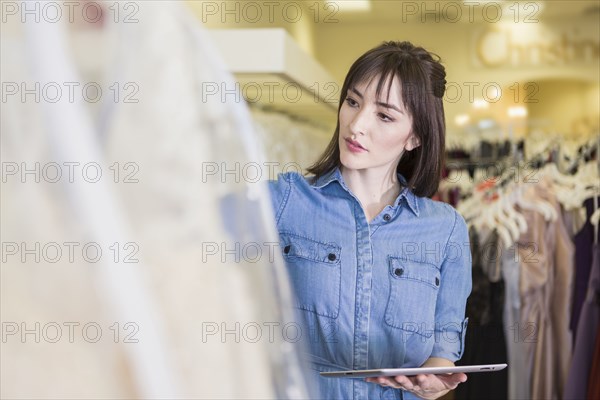 Hispanic entrepreneur using digital tablet in bridal shop