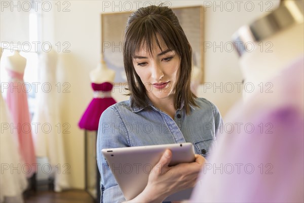 Hispanic entrepreneur using digital tablet in bridal shop