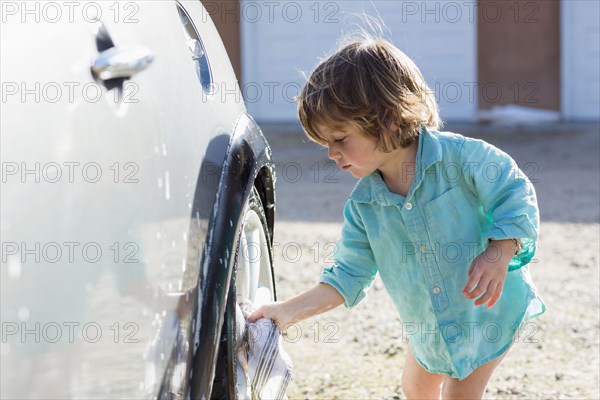 Caucasian boy washing car