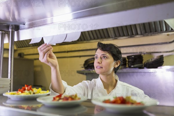 Caucasian chef reading orders in restaurant kitchen