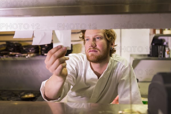 Caucasian chef reading orders in restaurant kitchen