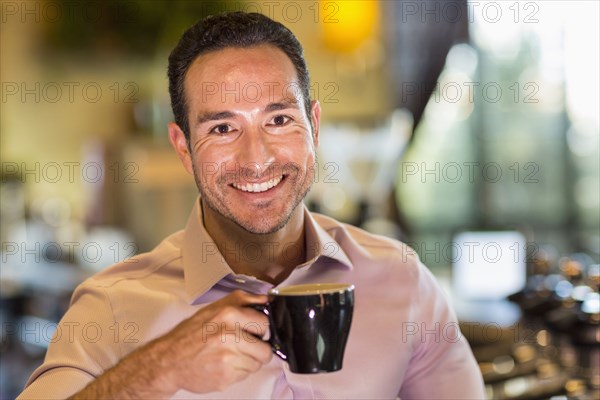 Hispanic barista drinking coffee in coffee shop