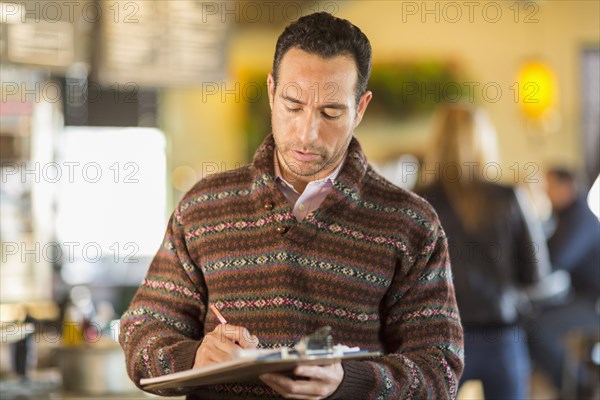 Hispanic businessman writing in coffee shop