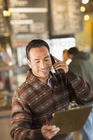 Hispanic businessman talking on telephone in coffee shop