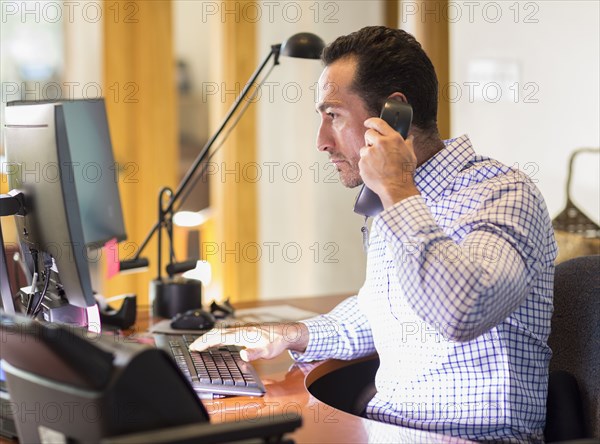 Hispanic businessman talking on telephone in office