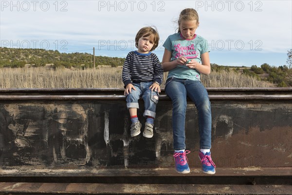 Caucasian brother and sister sitting outdoors