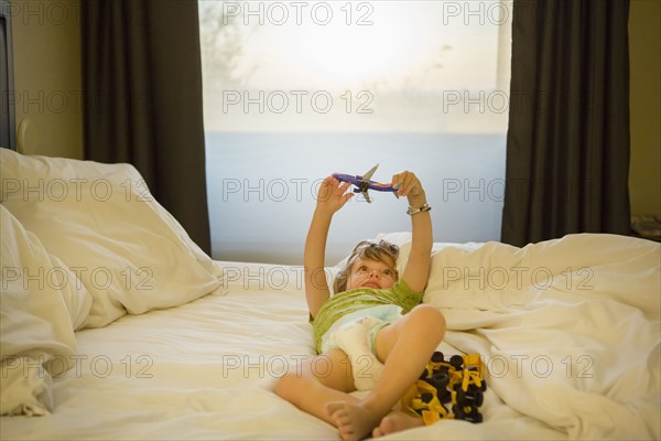 Caucasian boy playing with airplane on bed