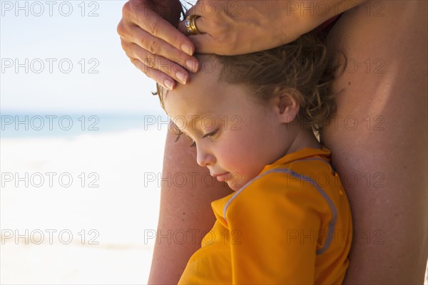 Caucasian boy leaning on legs of mother