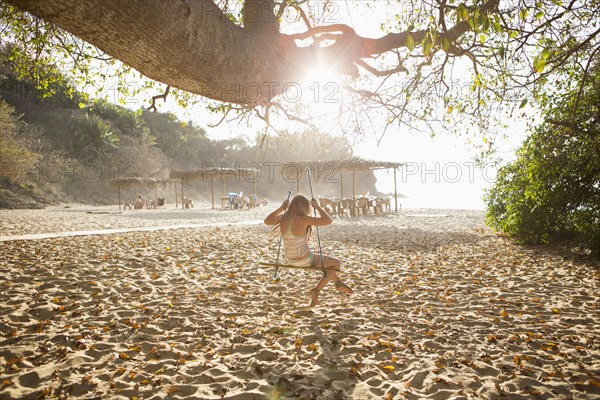 Caucasian girl sitting on tree swing