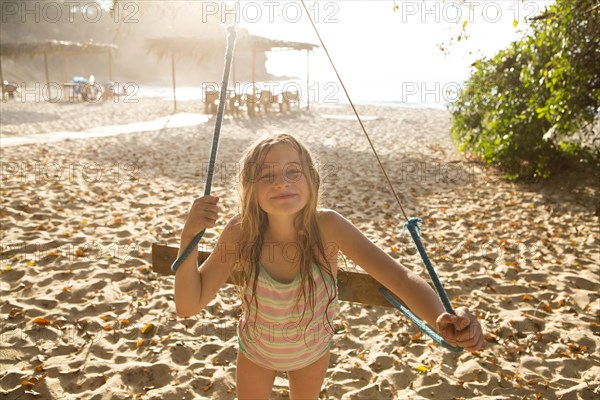 Caucasian girl playing on tree swing