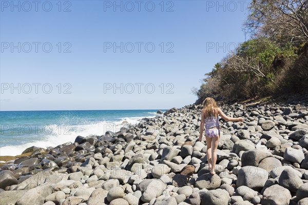 Caucasian girl walking on rocks at beach