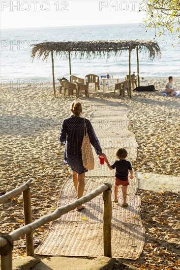 Caucasian mother and son walking on path to beach