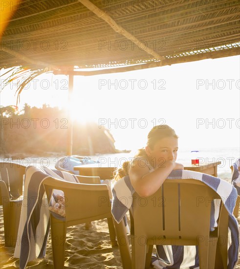 Caucasian girl sitting in chair at beach