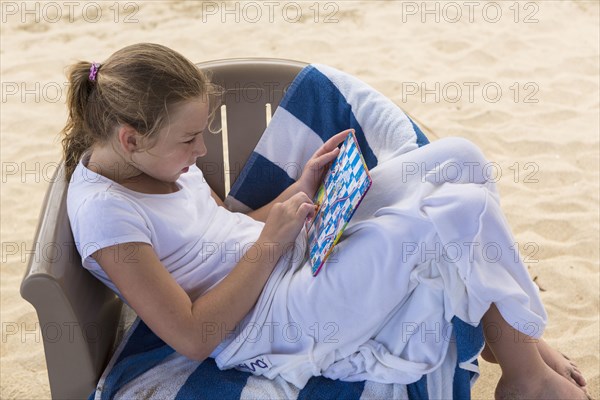 Caucasian girl sitting in beach chair playing game
