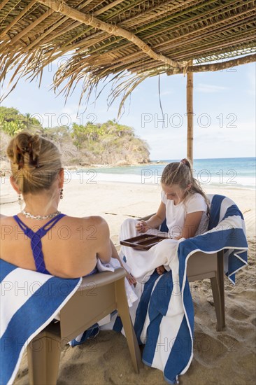 Caucasian mother and daughter playing backgammon at beach