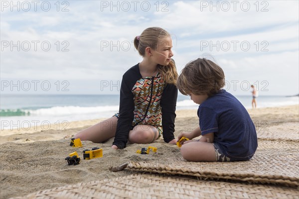 Caucasian brother and sister playing with toys at beach