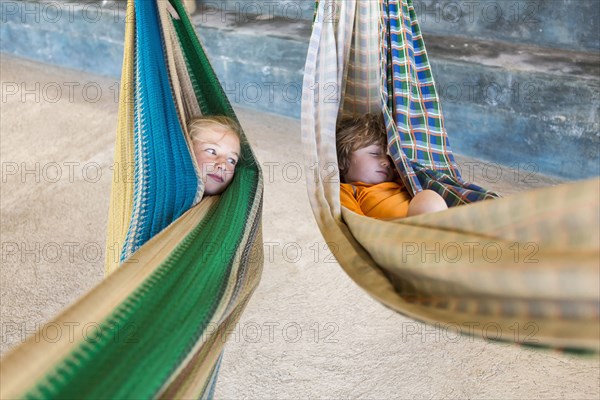 Caucasian girl in hammock checking on sleeping brother