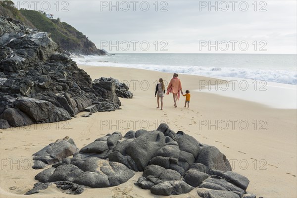 Caucasian mother and children walking on beach