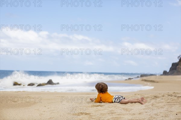 Caucasian boy laying on beach