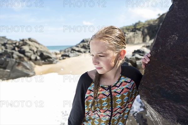 Caucasian girl leaning on rock at beach