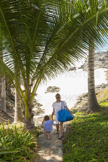 Caucasian mother and sun descending staircase to beach