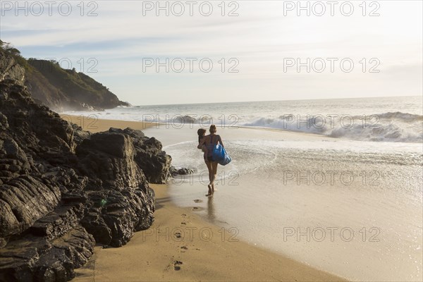 Caucasian mother carrying son on beach