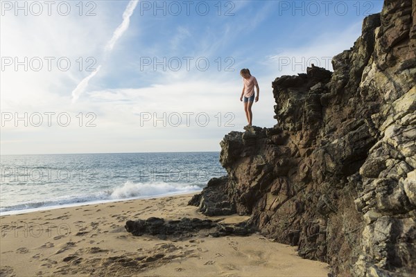 Caucasian girl standing on rocks at beach