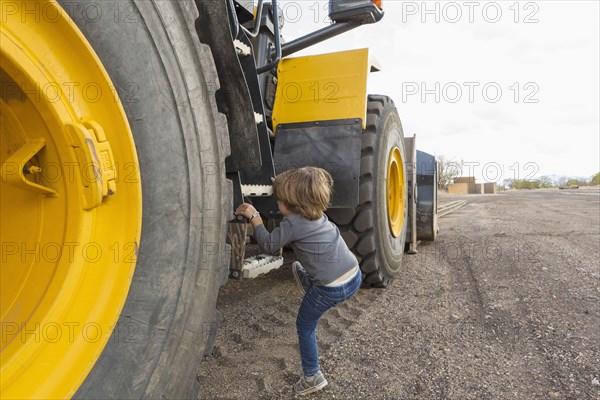 Caucasian boy climbing ladder on tractor