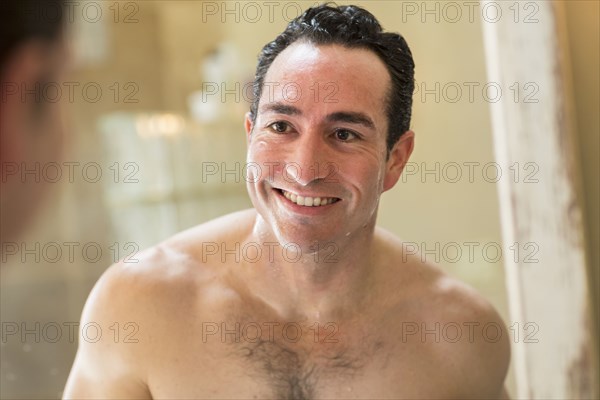 Clean-shaven Hispanic man smiling in mirror