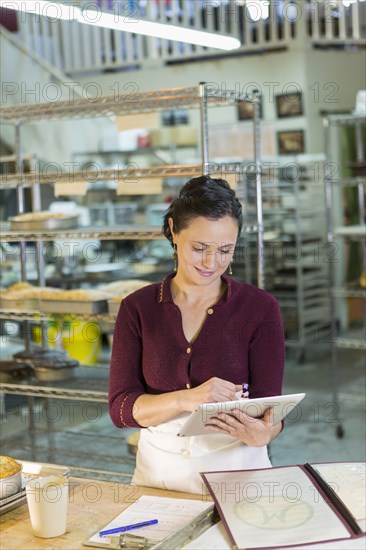 Caucasian woman using digital tablet in bakery