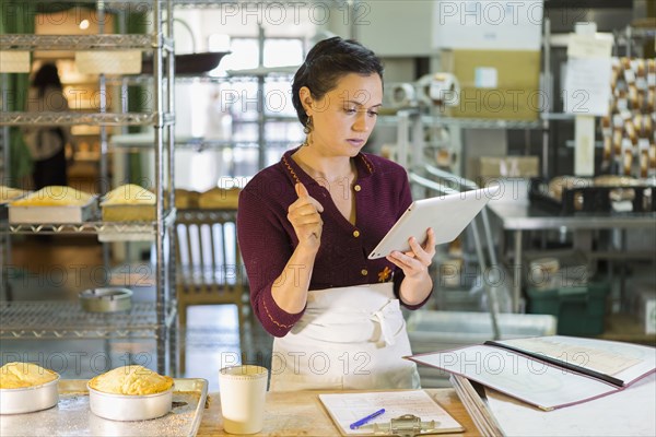 Caucasian woman using digital tablet in bakery