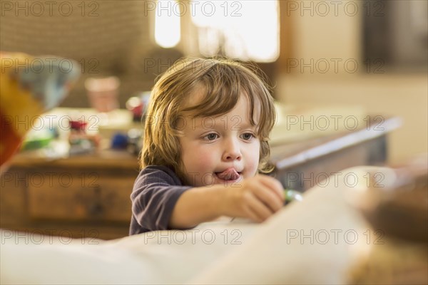 Caucasian boy with tongue out playing with toy