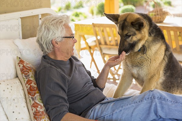 Caucasian man petting dog on patio