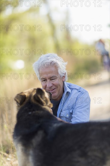 Caucasian man petting dog dirt road