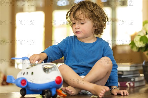 Caucasian boy playing with toy airplane on floor