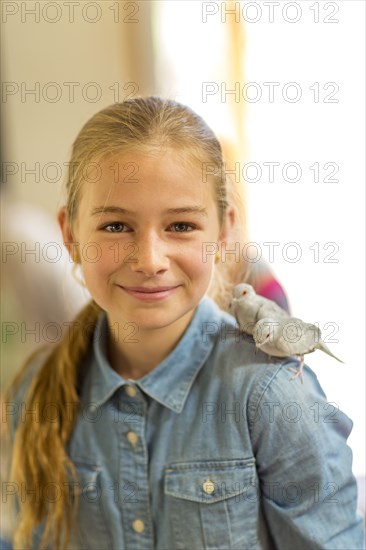 Caucasian girl with two pet birds standing on shoulder