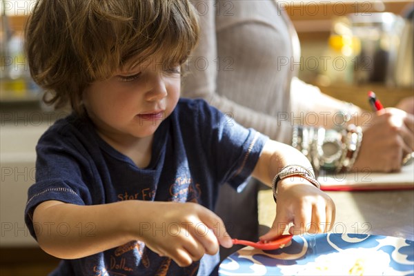 Caucasian boy eating food with plastic spoon